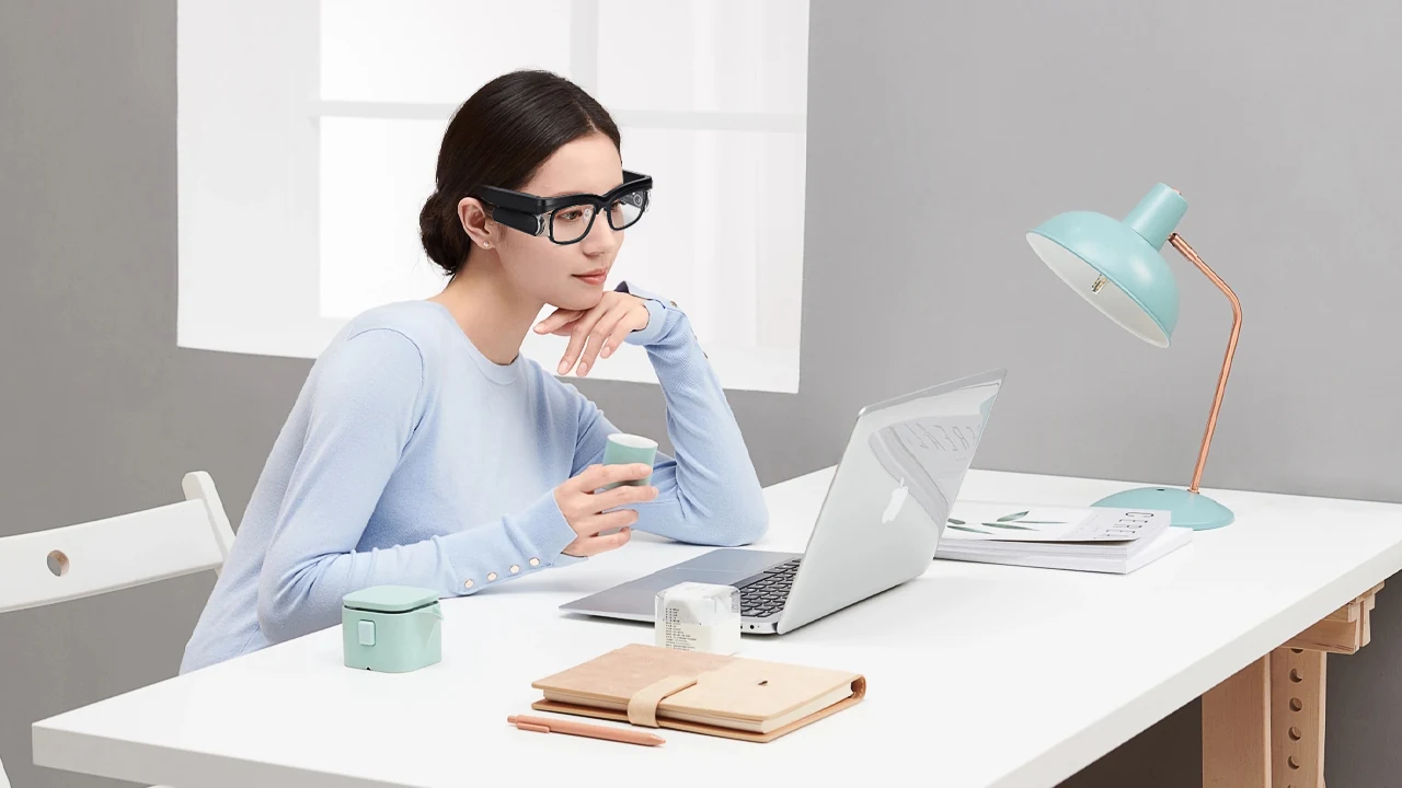 A woman wearing the Gen2 eyewear while seated at a laptop